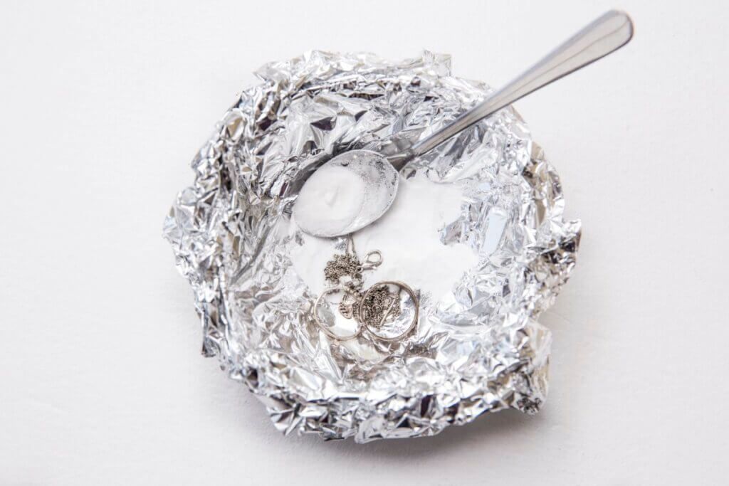 A Solution Of Baking Soda(sodium Bicarbonate) And Warm Water Will Remove The Tarnish From Silver When The Silver Is In Contact With A Piece Of Aluminium Tin Foil. Pouring Hot Water Over Silver.